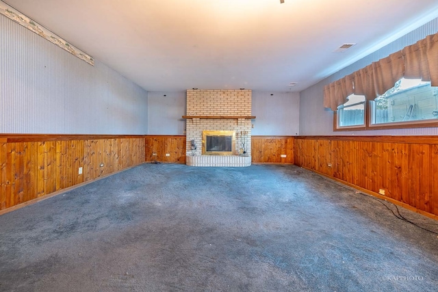 unfurnished living room featuring wood walls, carpet floors, and a fireplace