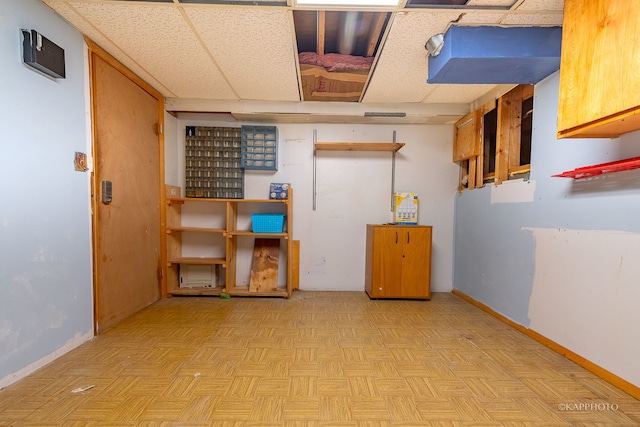 basement featuring a paneled ceiling and light parquet floors