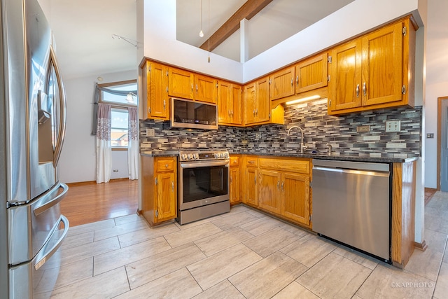 kitchen featuring tasteful backsplash, appliances with stainless steel finishes, sink, light wood-type flooring, and lofted ceiling with beams