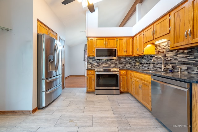 kitchen with appliances with stainless steel finishes, sink, lofted ceiling, dark stone counters, and decorative backsplash