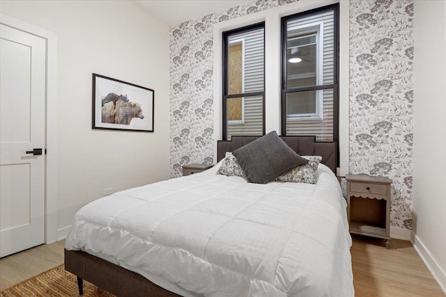 bedroom with ensuite bath, wallpapered walls, and baseboards