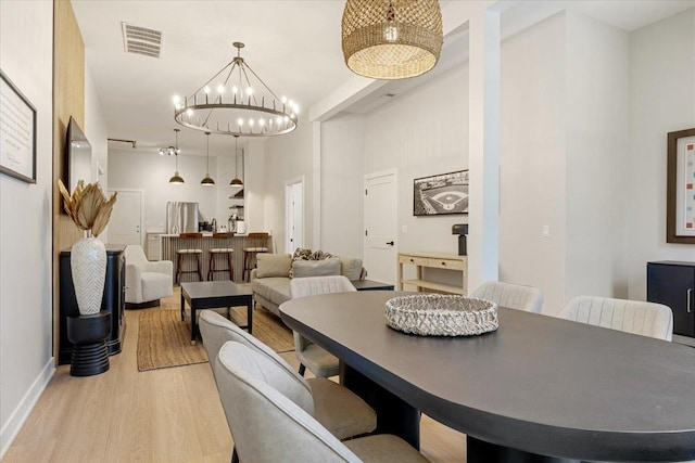 living area with an inviting chandelier, light wood finished floors, and baseboards
