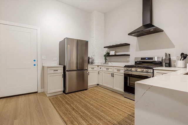 kitchen featuring wall chimney range hood, light wood-style floors, stainless steel appliances, a peninsula, and visible vents