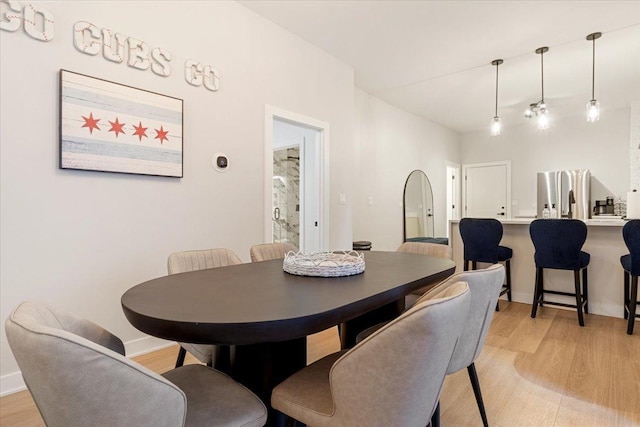 living area featuring baseboards, a chandelier, and light wood finished floors