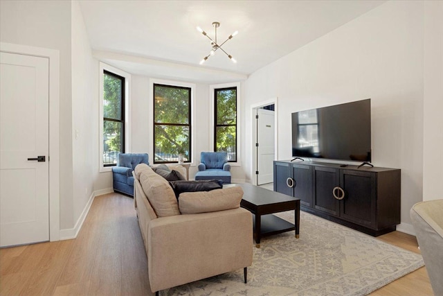 living area with baseboards, a chandelier, and light wood-style floors
