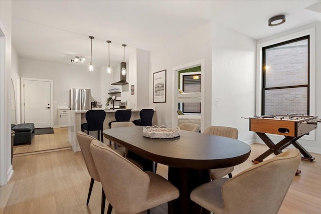 dining area featuring a chandelier, light wood-style flooring, and baseboards