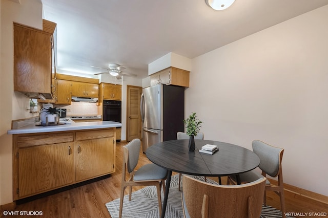 kitchen featuring stainless steel refrigerator, tasteful backsplash, ceiling fan, oven, and wood-type flooring