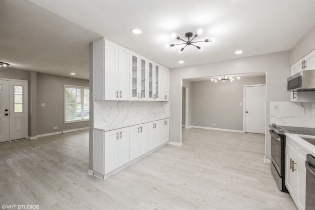 kitchen featuring stainless steel appliances, decorative backsplash, light wood-type flooring, and white cabinets