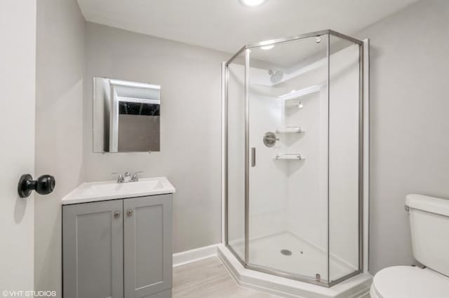 bathroom with a shower with door, hardwood / wood-style floors, vanity, and toilet