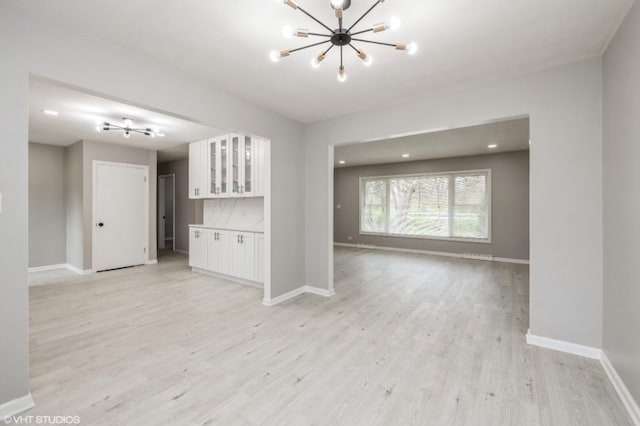 unfurnished living room with a notable chandelier and light hardwood / wood-style floors