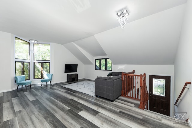 living room with a notable chandelier, wood-type flooring, and vaulted ceiling