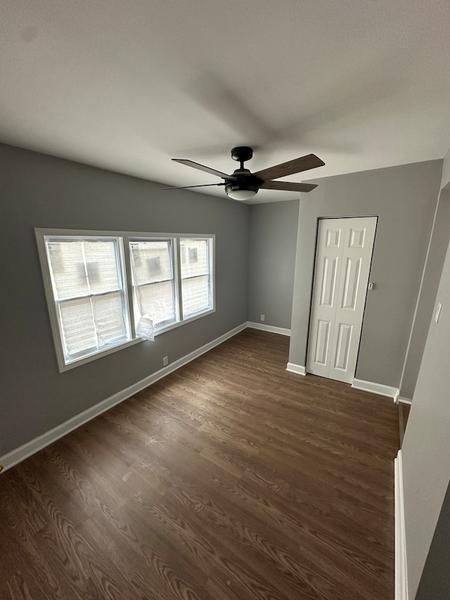 empty room with ceiling fan and dark wood-type flooring