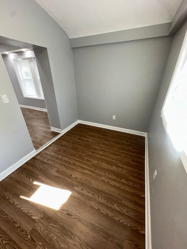 empty room with dark hardwood / wood-style floors and lofted ceiling