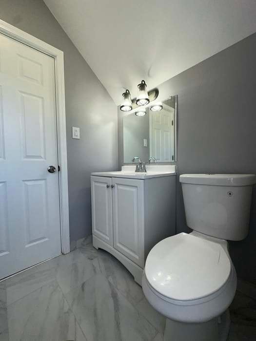 bathroom with vanity, toilet, and vaulted ceiling