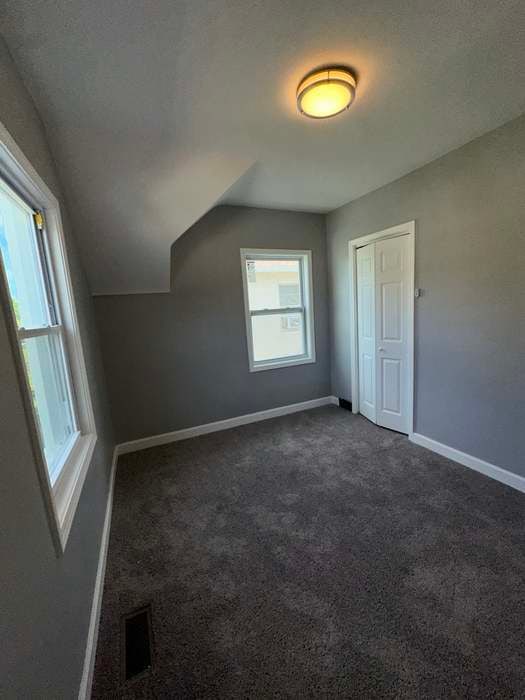 bonus room with dark carpet and lofted ceiling