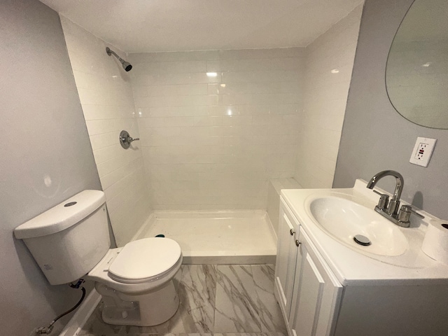 bathroom with a tile shower, vanity, and toilet