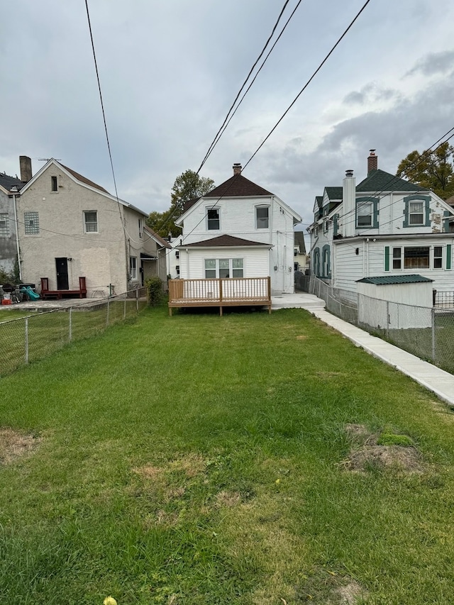 rear view of property with a lawn and a deck