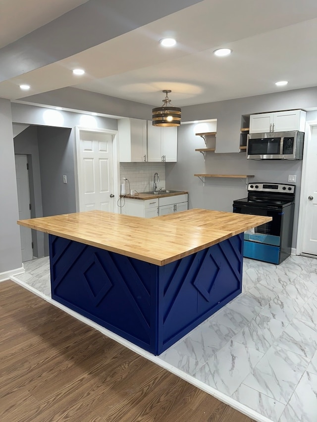 kitchen featuring butcher block counters, hanging light fixtures, light wood-type flooring, white cabinetry, and stainless steel appliances