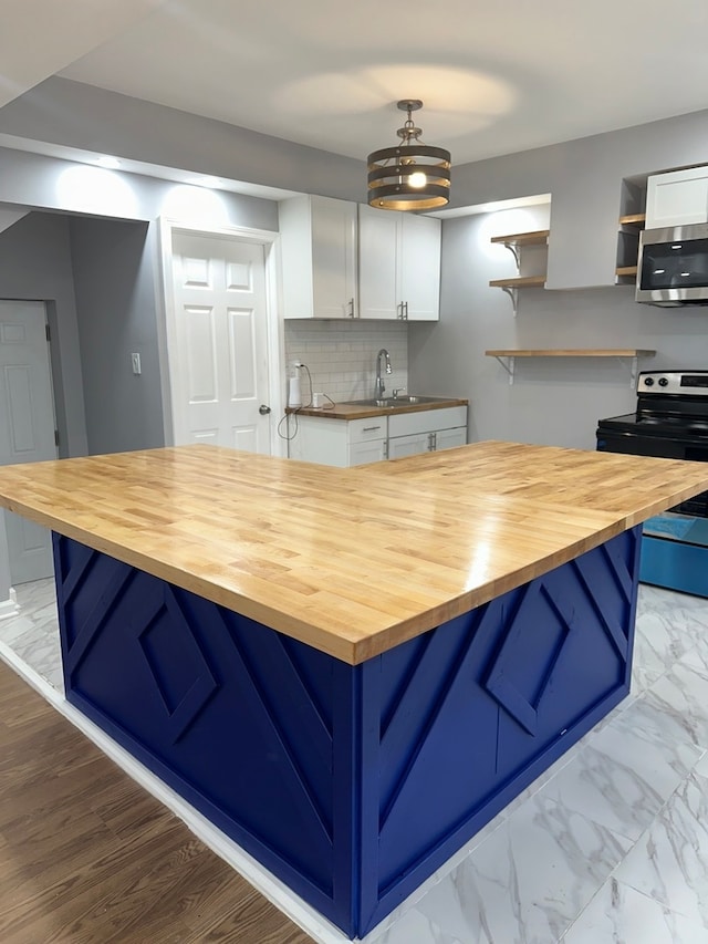 kitchen featuring butcher block counters, white cabinetry, pendant lighting, a breakfast bar area, and appliances with stainless steel finishes