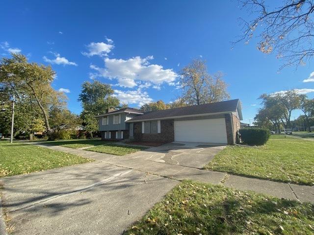 tri-level home with a garage, driveway, and a front yard