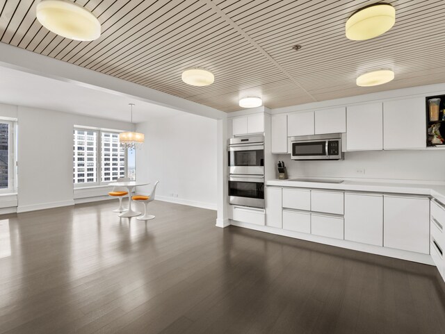 kitchen with stainless steel appliances, pendant lighting, white cabinets, dark wood-type flooring, and a chandelier