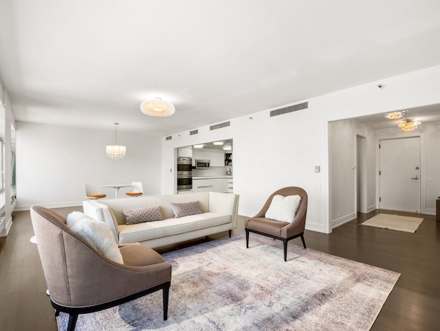 living room featuring a notable chandelier and dark hardwood / wood-style flooring