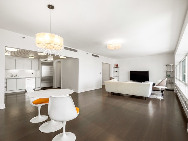 living room featuring dark wood-type flooring, a notable chandelier, and sink