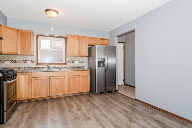 kitchen featuring backsplash, sink, appliances with stainless steel finishes, and light hardwood / wood-style floors