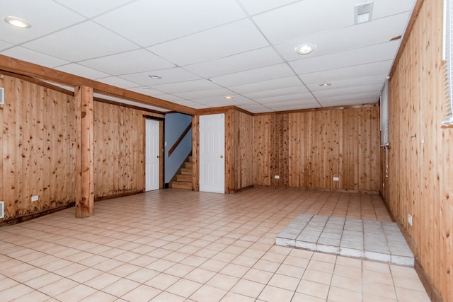 spare room featuring a drop ceiling and wooden walls