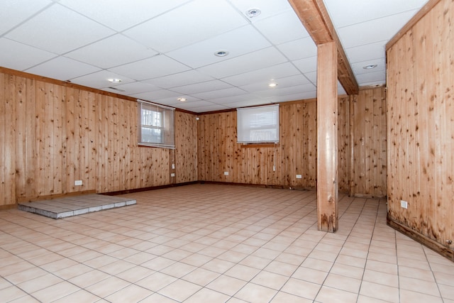 basement with a drop ceiling and wood walls