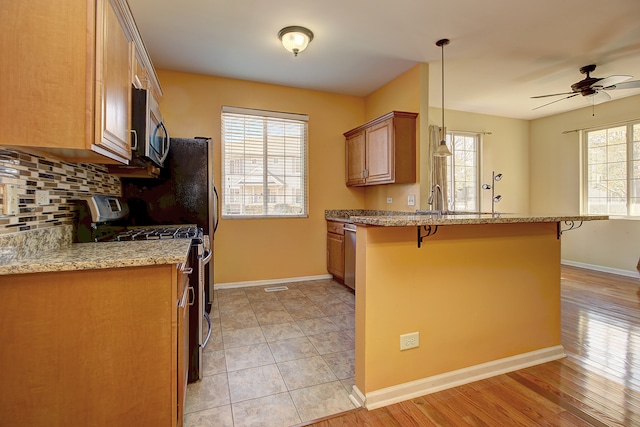 kitchen featuring a kitchen breakfast bar, a healthy amount of sunlight, and black gas range oven