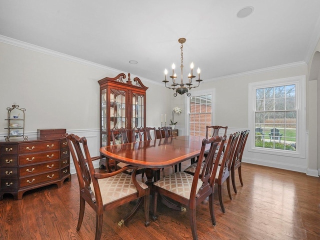 dining area featuring crown molding, dark wood-type flooring, and an inviting chandelier