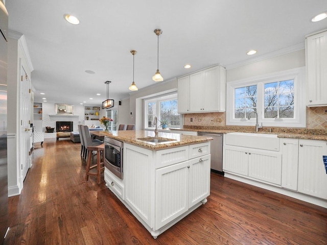 kitchen featuring appliances with stainless steel finishes, dark hardwood / wood-style floors, white cabinetry, and an island with sink