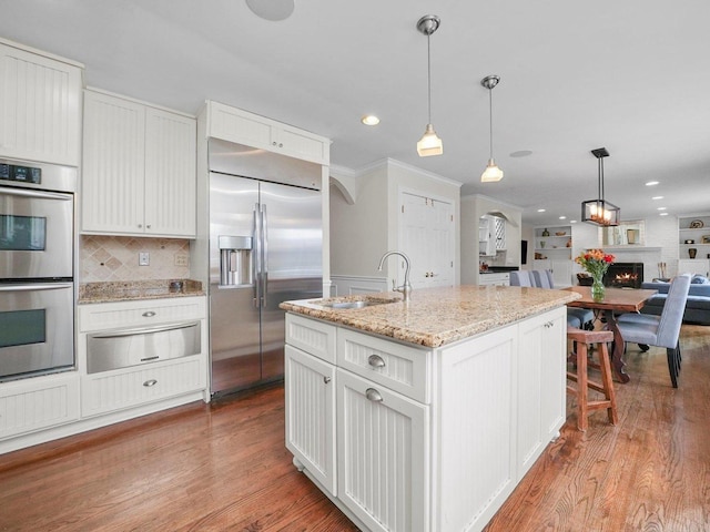 kitchen featuring white cabinets, appliances with stainless steel finishes, light hardwood / wood-style flooring, and a kitchen island with sink