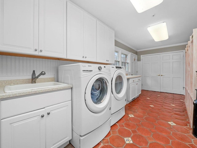 laundry area featuring washing machine and dryer, crown molding, sink, and cabinets