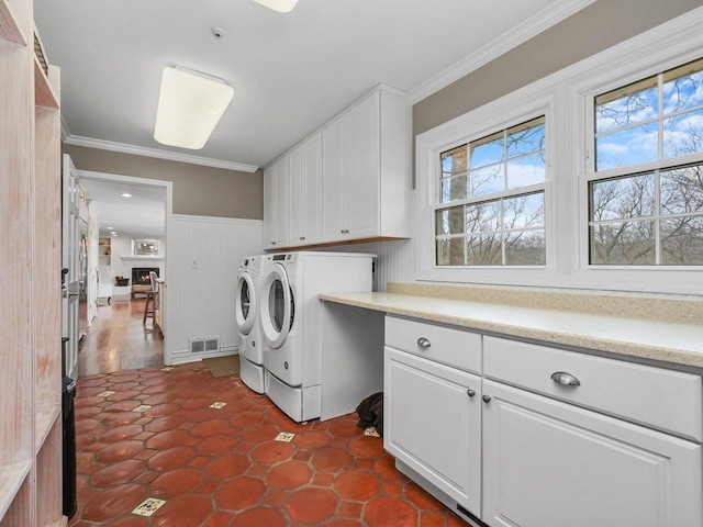 washroom with wood walls, cabinets, ornamental molding, and washing machine and clothes dryer