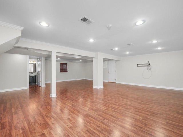 basement with hardwood / wood-style flooring and crown molding