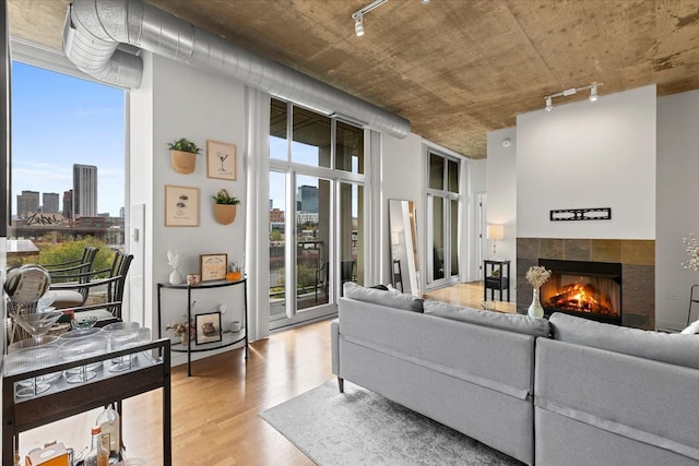 living room featuring hardwood / wood-style floors, rail lighting, a tile fireplace, and a wealth of natural light