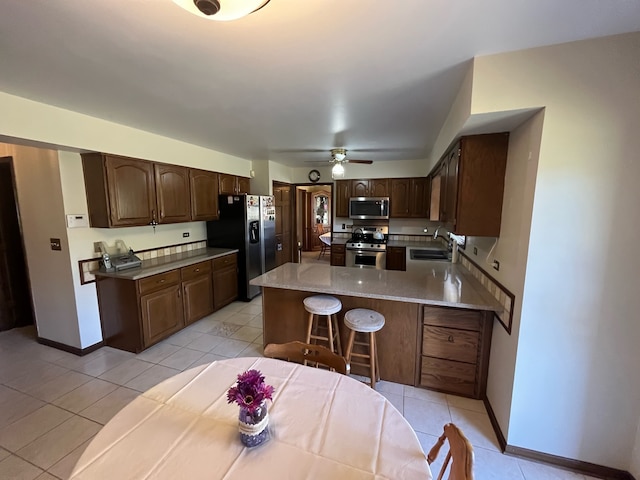 kitchen with a breakfast bar area, sink, stainless steel appliances, and light tile patterned floors