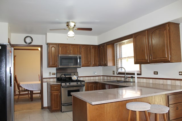 kitchen featuring appliances with stainless steel finishes, kitchen peninsula, sink, and ceiling fan