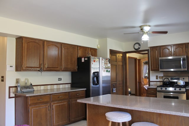 kitchen with a breakfast bar, stainless steel appliances, and ceiling fan