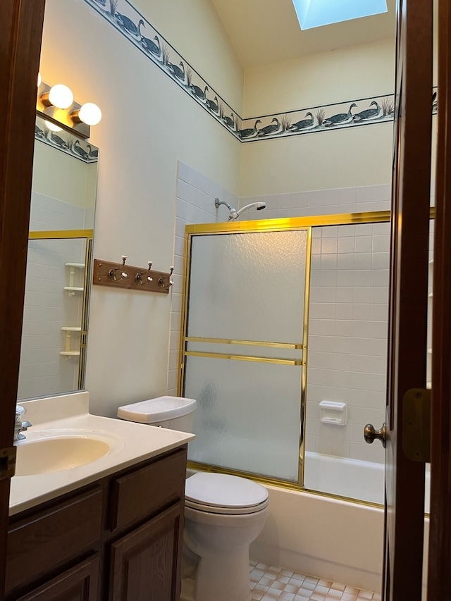 full bathroom with vanity, toilet, combined bath / shower with glass door, and a skylight