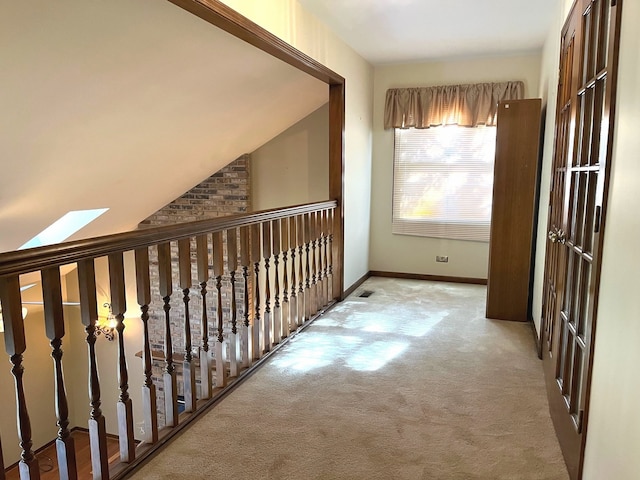 hall featuring lofted ceiling with skylight and light colored carpet