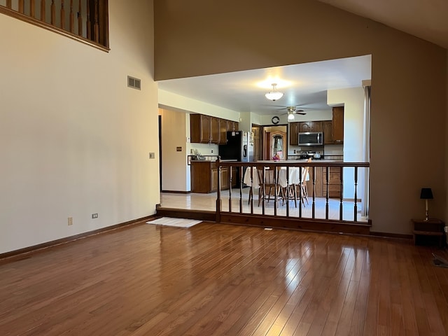 living room featuring wood-type flooring, high vaulted ceiling, and ceiling fan