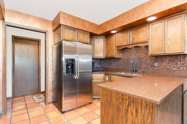 kitchen featuring kitchen peninsula, sink, stainless steel fridge with ice dispenser, light tile patterned flooring, and tasteful backsplash