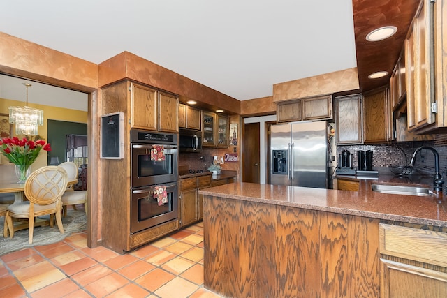 kitchen with appliances with stainless steel finishes, kitchen peninsula, decorative backsplash, and sink