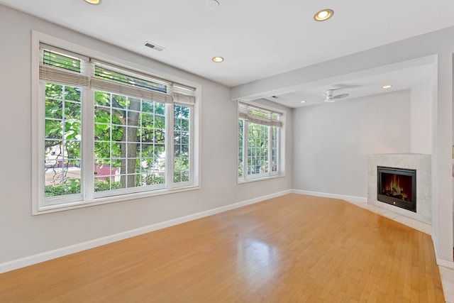 unfurnished living room with light hardwood / wood-style floors, a premium fireplace, and ceiling fan