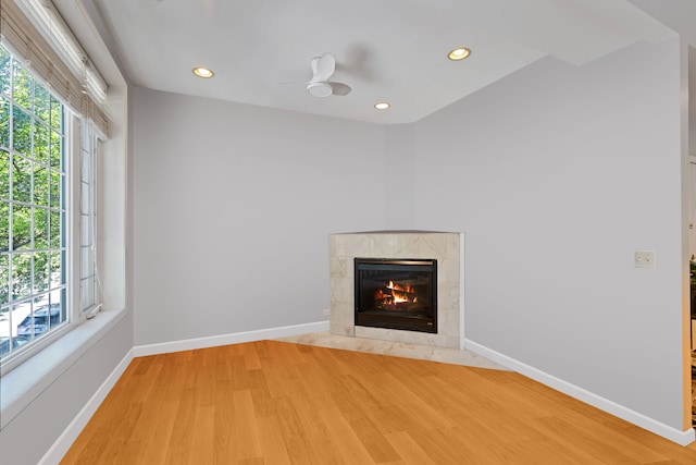 interior details with ceiling fan, wood-type flooring, and a premium fireplace