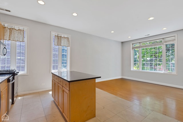 kitchen with appliances with stainless steel finishes, a center island, and light wood-type flooring