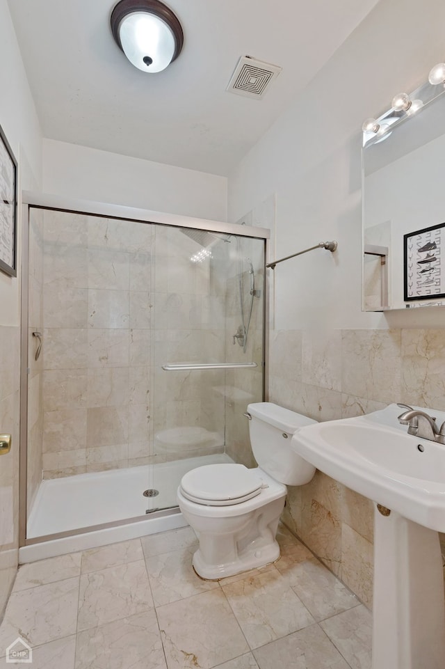 bathroom with toilet, an enclosed shower, and tile walls